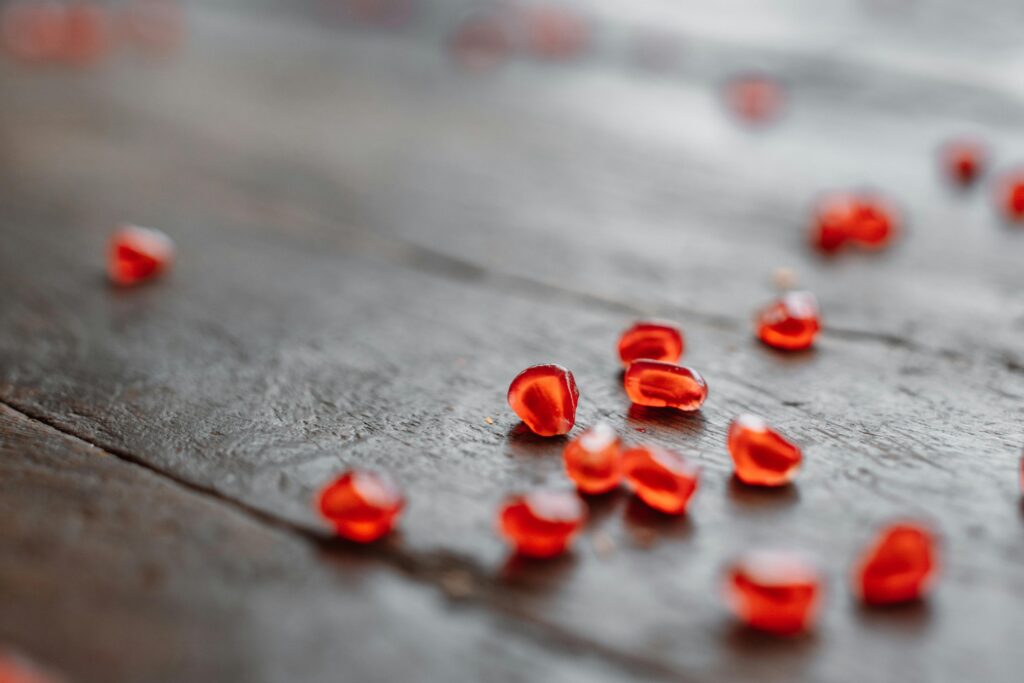 Vibrant pomegranate seeds scattered on a rustic wooden surface.